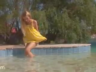 Blek blond tenåring med oppkvikket pupper stripping av den basseng